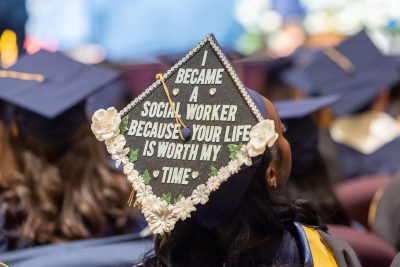 Image of mortarboard worn by student at the 2023 School of Social Work Commencement ceremony with words, "I became a social worker because your life is worth my time."