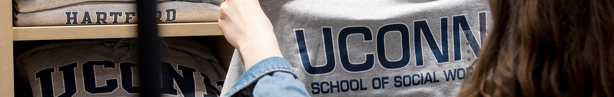 student holding up school of social work sweatshirt